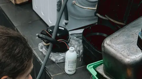 Technician Handling Refrigerant in Workshop Setting