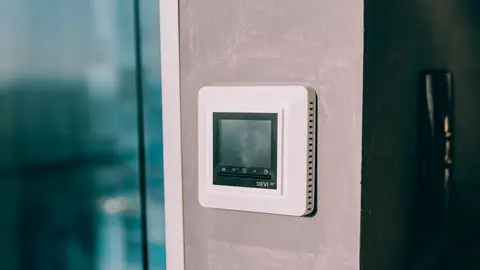 A Digital Thermostat on a Wall next to a Window