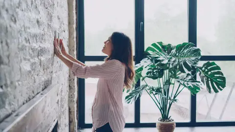 Woman Adjusting Thermostat in Bright Indoor Setting