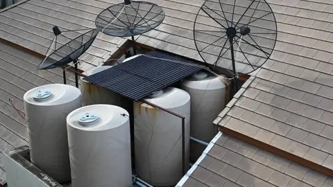 DZ6 2947 Rooftop view in Pattaya water storage tanks and satellite dishes tucked into a tiled roof cavity