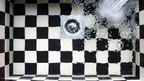 Water Flowing on White and Black Checked Bath Tub