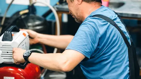 Repairman Fixing Machine in Workshop Interior