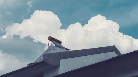 Solar Water Heater on Rooftop Against Cloudy Sky