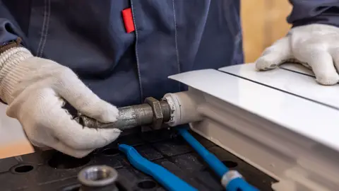 Professional Plumber Installing a Radiator Pipe