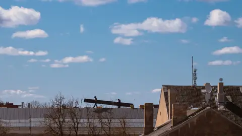 Silhouetted Workers on Rooftop Against Blue Sky