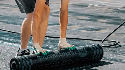 Man Installing Roofing Felt on Building Rooftop