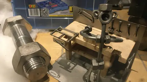 Shop window decoration with large bolt and nut, and model of mechanical workbench with 'iron man'