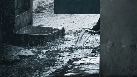 Rain Water Flowing From a Pipe at a House Entrance